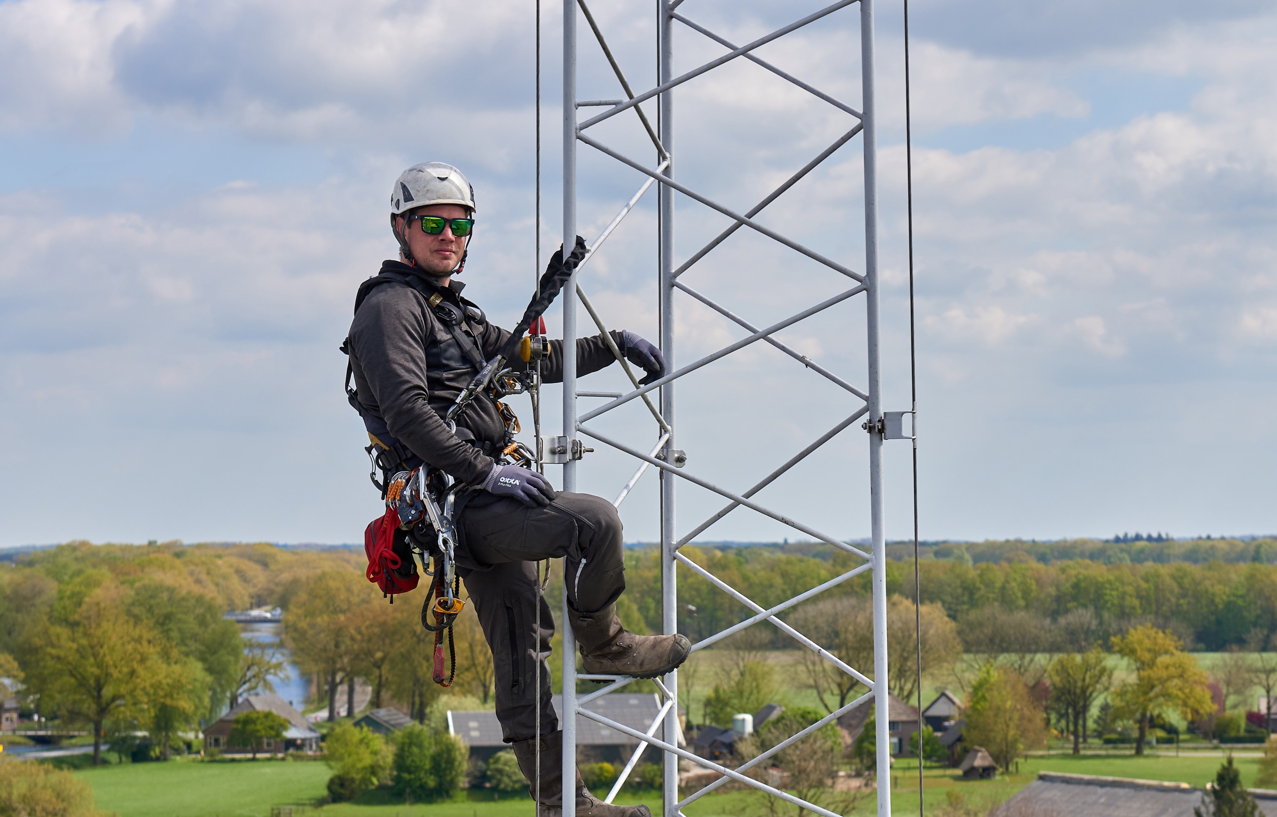 Een man hangt gezekerd in een hoge mast