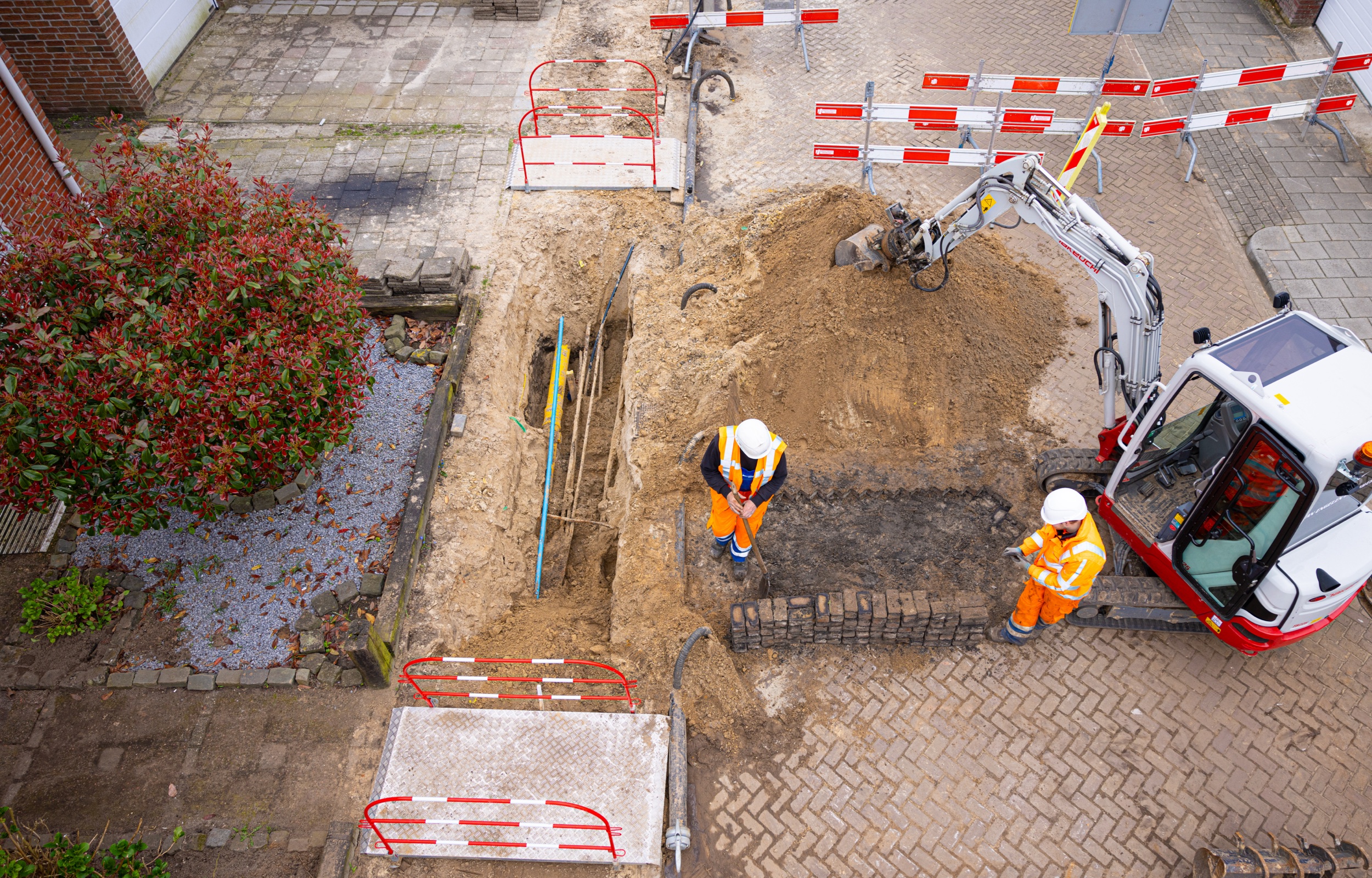 Luchtopname van twee mannen die kabels leggen in een straat